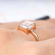Radiant diamond ring showcased on finger with pink background