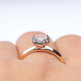 Zoomed view of four prong diamond ring set against a soft pink background