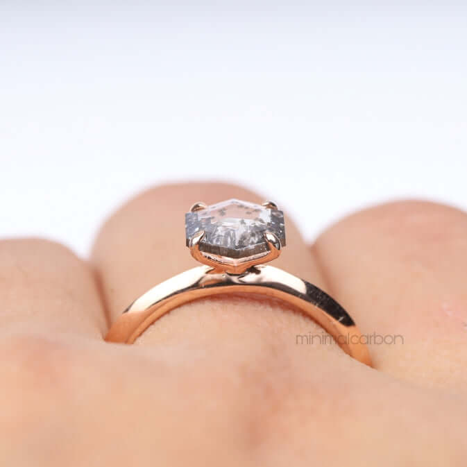 Zoomed view of four prong diamond ring set against a soft pink background
