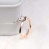 Elegant solitaire diamond ring in four prong setting standing upright on soft surface