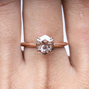 Detailed close-up of a silver four prong ring with reflection on glossy white base