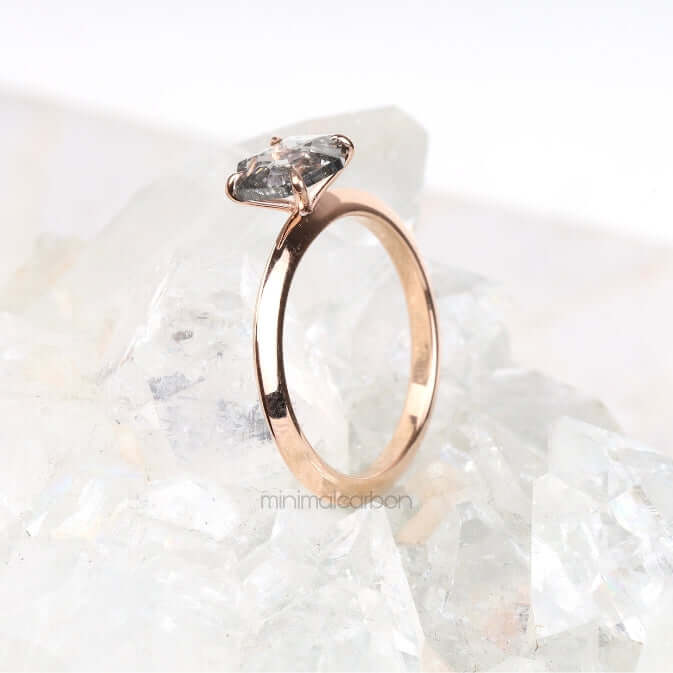 Gold four prong solitaire ring with round diamond on light marble background