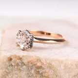 Side profile of rose gold four prong engagement ring worn on finger